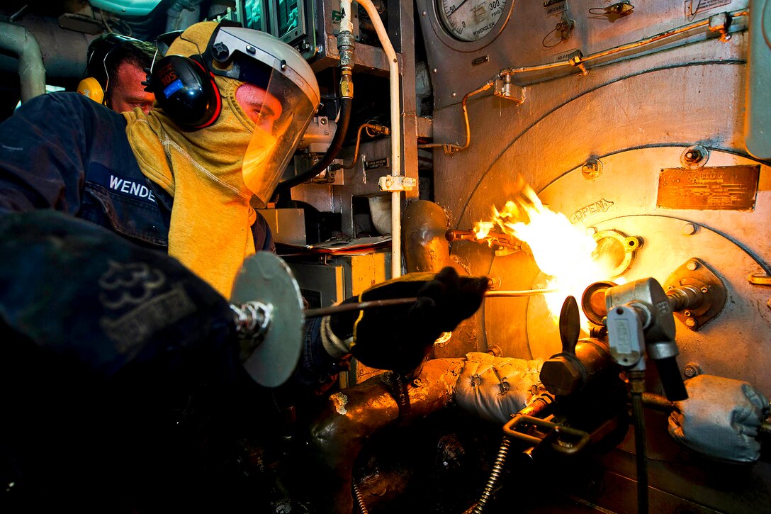 U.S. Navy Petty Officer 3rd Class Alexander Wendell inserts a torch into a boiler during a manual boiler check aboard the amphibious dock landing ship USS Carter Hall in the Persian Gulf, July 8, 2013. The Hall, part of the Kearsarge Amphibious Ready Group, is supporting maritime security operations and theater security cooperation efforts in the U.S. 5th Fleet area of responsibility.