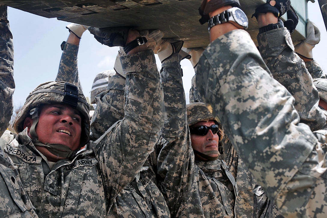 Soldiers lift a beam while learning to assemble a medium girder bridge during annual training on Camp Santiago Joint Maneuver Training Center in Salinas, Puerto Rico, July 9, 2013.