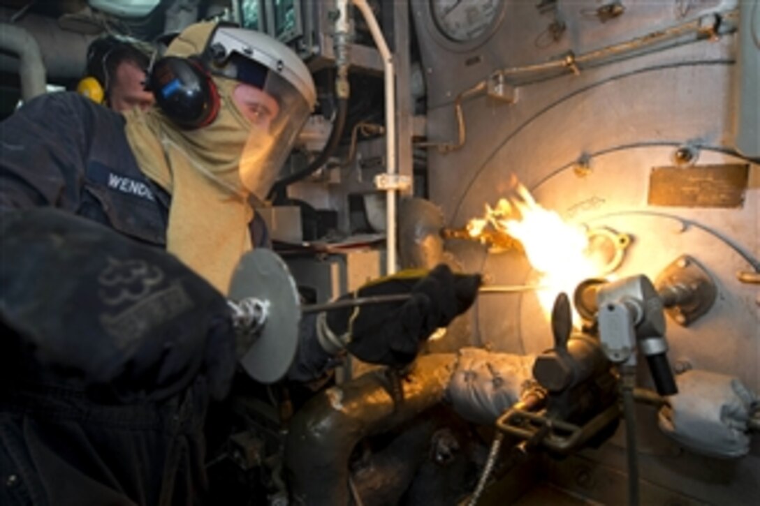 U.S. Navy Petty Officer 3rd Class Alexander Wendell inserts a torch into a boiler during a manual boiler check aboard the amphibious dock landing ship USS Carter Hall (LSD 50) as the ship operates in the Persian Gulf on July 8, 2013.  The Carter Hall is part of the Kearsarge Amphibious Ready Group and is deployed to the 5th Fleet area of responsibility to conduct maritime security operations and theater security cooperation efforts.  