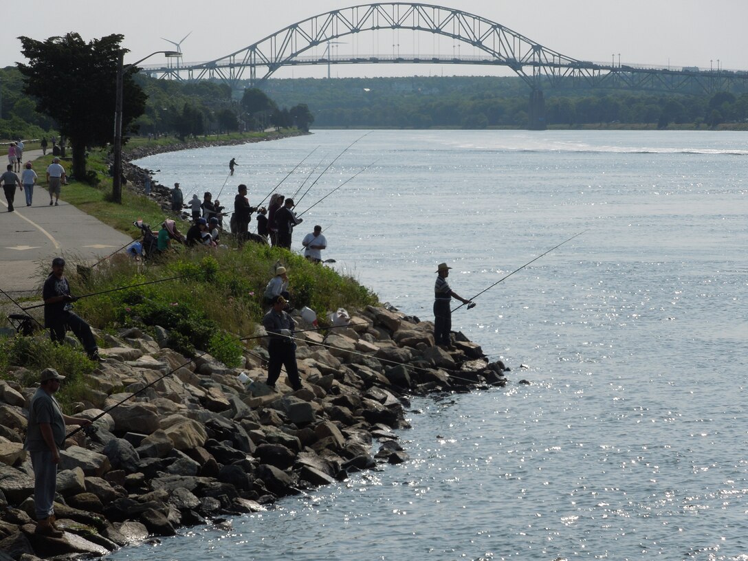 Anglers flock to the rocky shores of the Cape Cod Canal recreation area in Buzzard's Bay to try their hand at landing some fish on an overcast weekend.