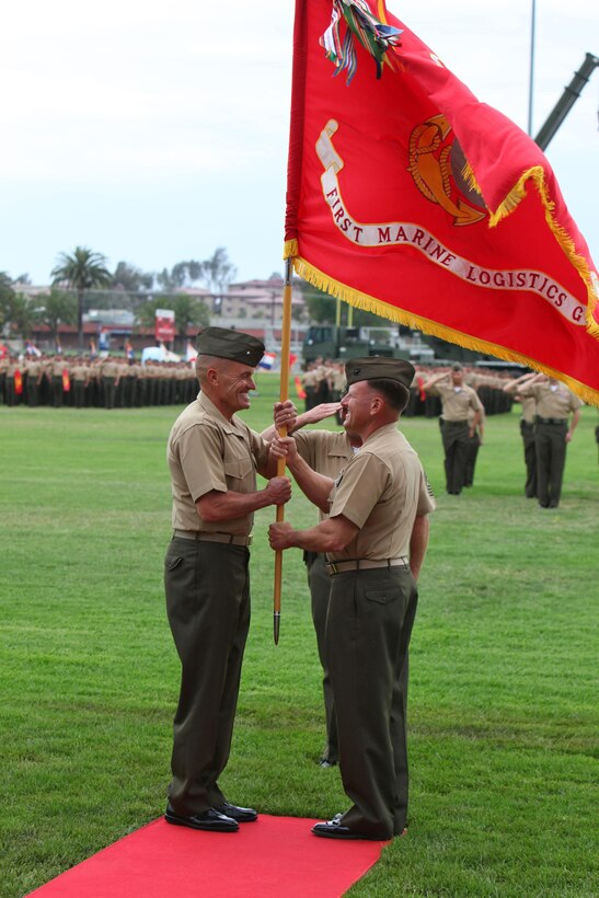 Major Gen. John J. Broadmeadow, right, outgoing commanding general, 1st Marine Logistics Group, relinquishes his command to Brig. Gen. Vincent A. Coglianese, left, during a change of command ceremony aboard Camp Pendleton, Calif., July 11, 2013. The passing of the unit’s battle colors symbolizes the transfer of authority and responsibility of command from one general officer to another. 
Major Gen. Broadmeadow, a native of Pawtucket, R.I., has served as the commanding general since June 2011.