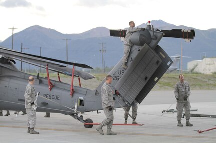 Alaska Air National Guardsmen from the 176th Aircraft Maintenance Squadron and the 176th Maintenance Squadron guide a HH-60 Pave Hawk helicopter on to a U.S. Air Force C-17 Globemaster III.