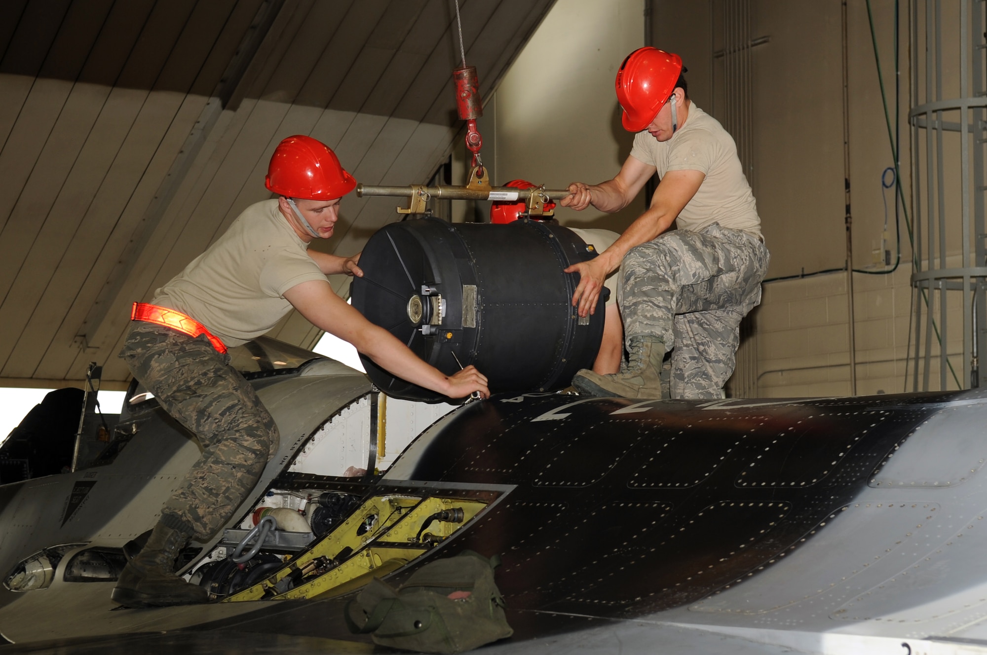 U.S Air Force Senior Airman Christopher Oullet and Airman 1st Class Joshua Samuelson, 354th Aircraft Maintenance Squadron weapons load crew members, install a drum in an F-16 Fighting Falcon July 9, 2013, Eielson Air Force Base, Alaska.  The drum holds together all the rounds in the gun system for the F-16 Fighting Falcon. (U.S. Air Force photo by Airman 1st Class Lauren-Taylor Levin/Released)