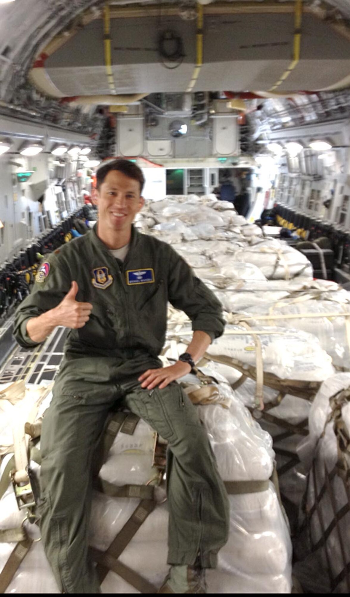 Maj. Michael Masuda, 313th Airlift Squadron, sits on a pallet stacked with rice headed to Haiti in June.  The humanitarian mission to Haiti carried the donated rice under authority of the Denton Amendement.  The same flight allowed the 446th Aeromedical Evacuation Squadron to conduct inflight training and for Reserve and active Airmen flight crew training. (Courtesy photo)