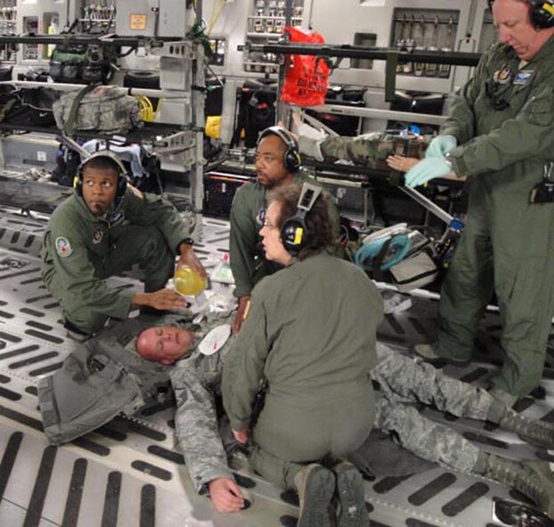 Senior Airman Marvin Howard (left to right), Tech. Sgt. John Tomas, Lt. Col. Kenneth Winslow, and Maj. Shelia Wojewodzki, all with the 446th Aeromedical Evacuation Squadron, run through an inflight medical drill with "patient" Master Sgt. Michael Pate, 446th Security Forces Squadron.  Sixteen 446th SFS Airmen  hitched a ride on an AES training flight to reach their own training opportunity at Fort Wolters, Texas in June.  Some then volunteered to supplement the AES training by fulfilling the roles of patients. (Courtesy photo)