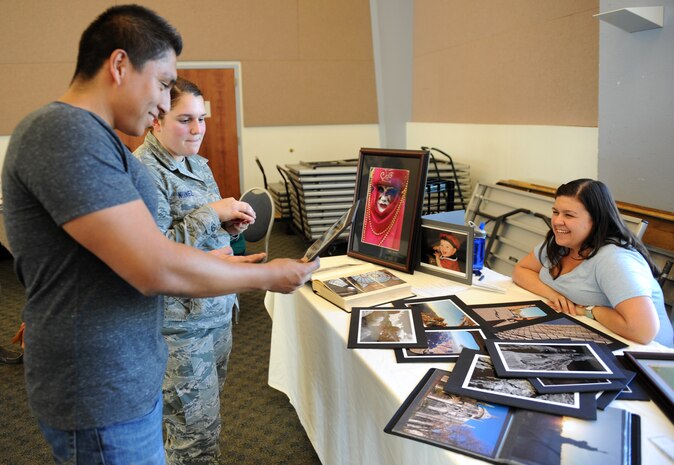 Airman 1st Class Gabriela Nunez and her husband Elias browse through some mounted photographs during the Vendor Fair at the Community Activity Center here July 11, 2013. Nearly 20 home based vendor attended the event. (U.S. Air Force photo by Staff Sgt. Robert M. Trujillo/ Released)