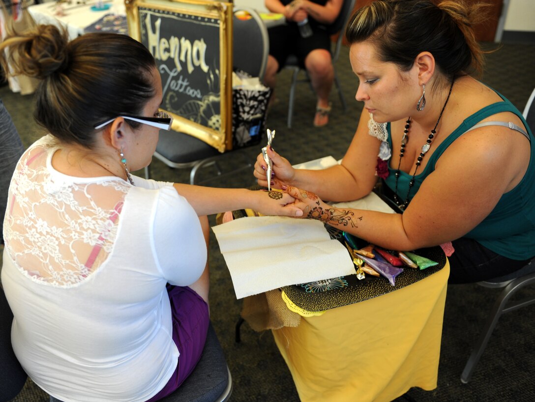 A vendor creates a henna tattoo on a customer during the Vendor Fair at the Community Activity Center here July 11, 2013. Many of the vendors are military spouses or dependents. (U.S. Air Force photo by Staff Sgt. Robert M. Trujillo/ Released)