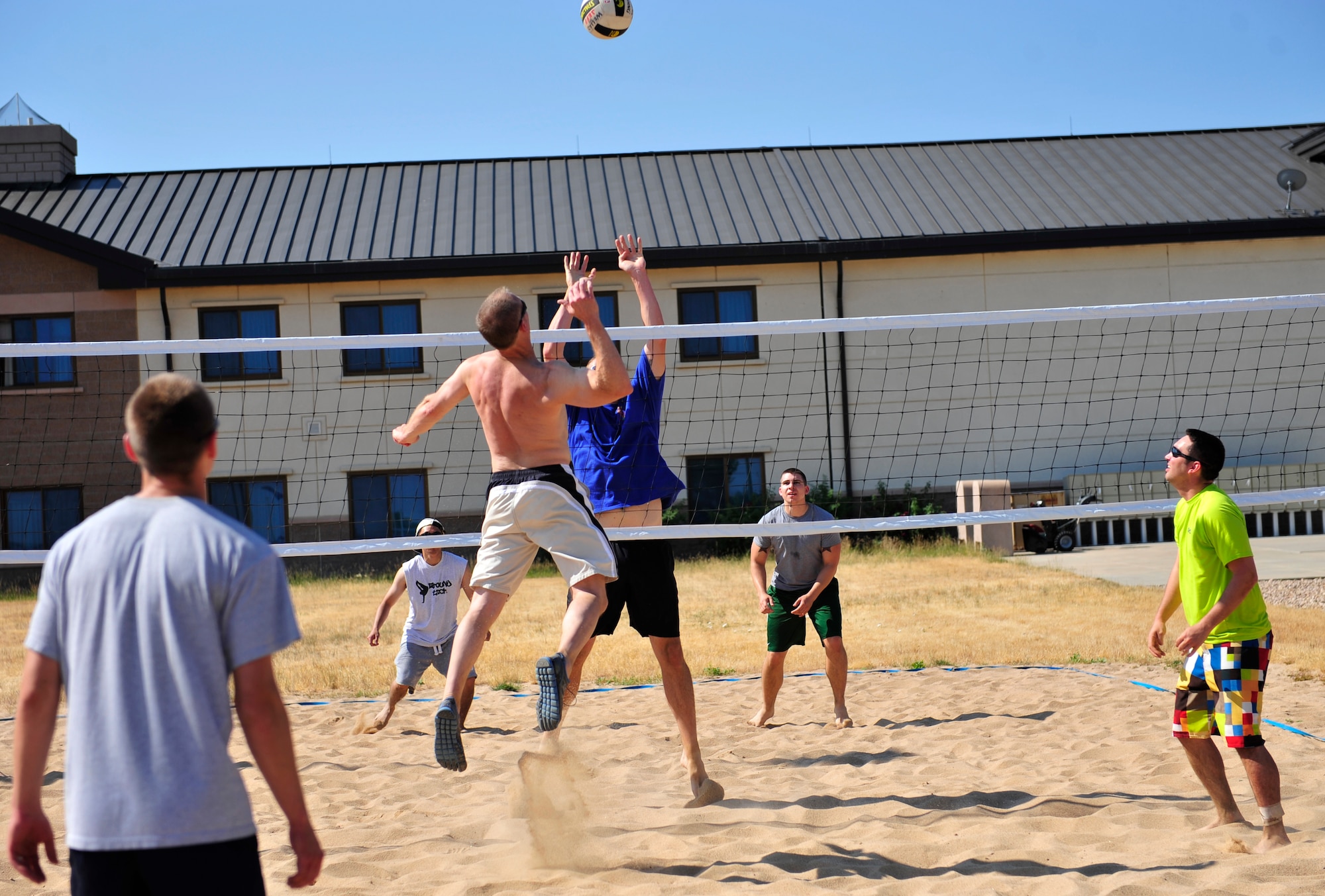 Jeffrey Welles, 460th Operations Support Squadron, center left, jumps to spike the ball against Mathew Holley, 460th OSS, who tries to block it during the annual four-on-four sand volleyball tournament July 11, 2013, at Buckley Air Force Base, Colo. The 460th OSS were victorious against their competition in the tournament. (U.S. Air Force photo by Airman 1st Class Darryl Bolden Jr./Released)
