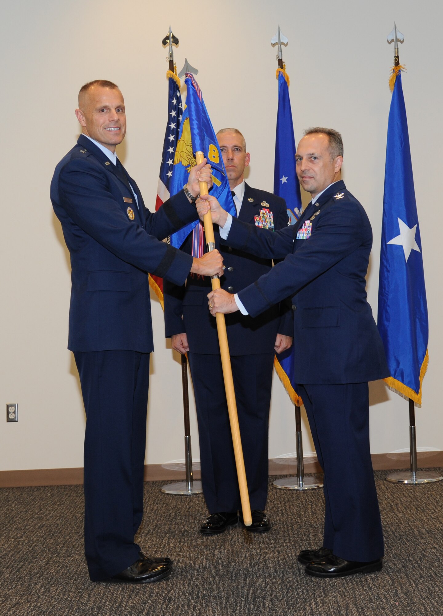 Brig. Gen. Brad Spacy, 81st Training Wing commander, passes the guidon to Col. George Tombe as he assumes command of the 81st Training Group during a change of command ceremony July 11, 2013, at the Roberts Consolidated Aircraft Maintenance Facility, Keesler Air Force Base, Miss.  Col. Maureen Smith was the outgoing 81st TRG commander.