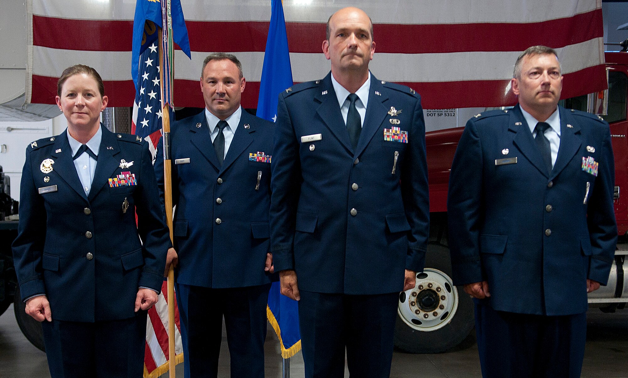 Cols. Tracey Hayes, 90th Missile Wing commander; Trevor Flint, 90th Maintenance Group commander; and Don Adams stand at attention shortly after Flint assumed command of the 90 MXG from Adams during a change-of-command ceremony in the group’s maintenance bays on F. E. Warren Air Force Base, Wednesday, July 3, 2013. Chief Master Sgt. Chriss Hart, 90th MXG chief enlisted manager, holds the group’s guidon. (U.S. Air Force photo by R.J. Oriez)