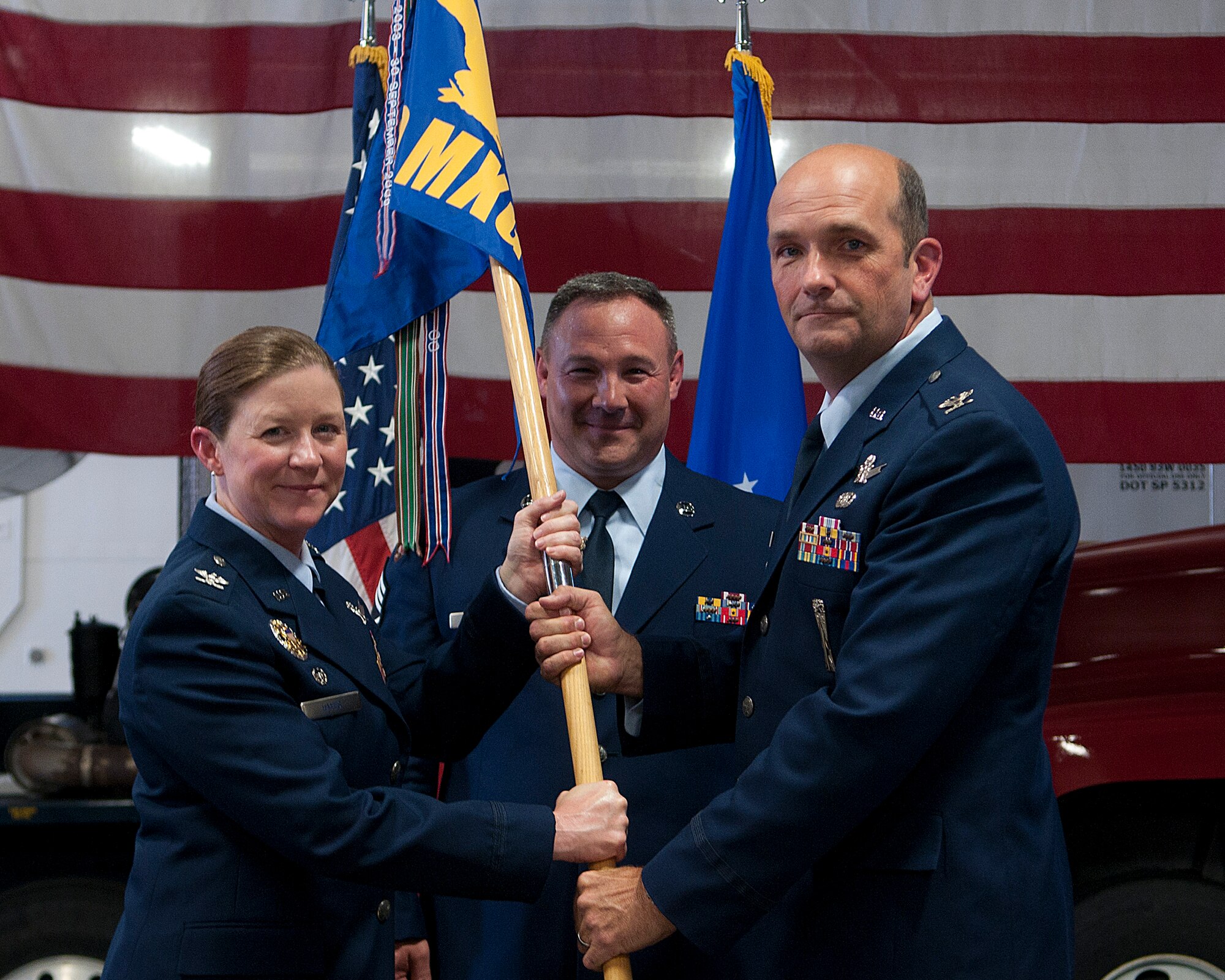Col. Tracey Hayes, 90th Missile Wing commander passes the 90th Maintenance Group guidon to Col. Trevor Flint as he assumes command of the 90th MXG during a ceremony in the group’s maintenance bays on F. E. Warren Air Force Base July 3, 2013. (U.S. Air Force photo by R.J. Oriez)