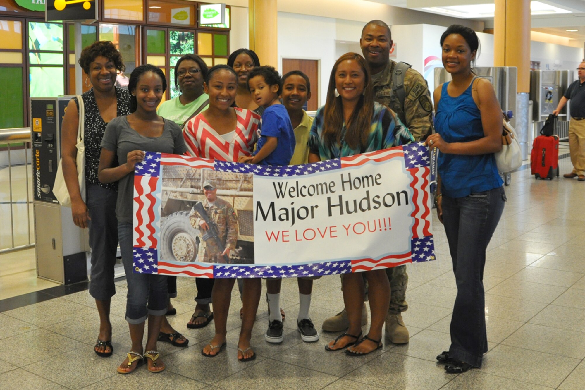 Maj. Quincy Hudson, 94th Airlift Wing protocol officer, welcomed home from a six-month deployment at Hartsfield-Jackson International Airport by his wife, Naomi, a host of family members July 11. Hudson served as the personnel officer for Camp Phoenix, Kabul, Afghanistan. (U.S. Air Force photo/James Branch)