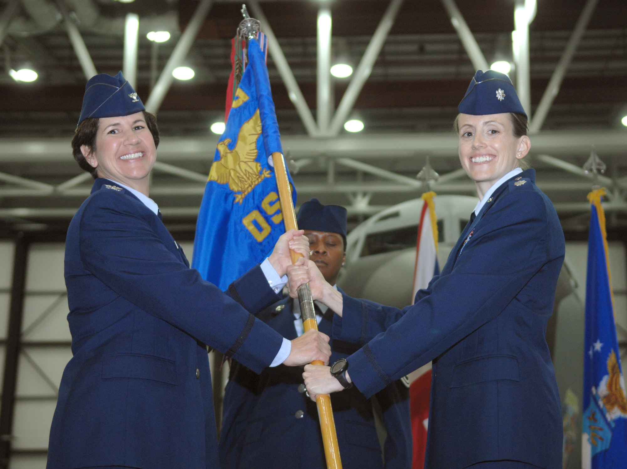 From right, Lt. Col. Heather Baldwin, 100th Operations Support Squadron commander, receives the 100th OSS guidon from Col. Nancy Bozzer, 100th Operations Group commander, during the 100th OSS change of command July 12, 2013, in Hanger 814 on RAF Mildenhall, England. Baldwin was previously the 100th Air Refueling Wing chief of safety. (U.S. Air Force photo by Airman 1st Class Dillon Johnston/Released)