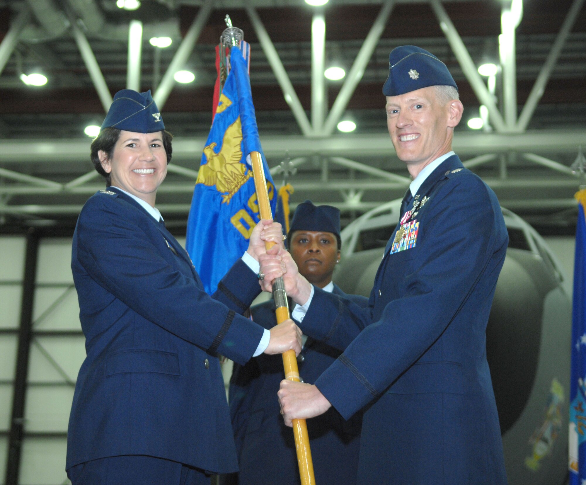 From right, Lt. Col. Christopher Bennett, 100th Operations Support Squadron commander, passes the 100th OSS guidon to Col. Nancy Bozzer, 100th Operations Group commander, during the 100th OSS change of command July 12, 2013, in Hanger 814 on RAF Mildenhall, England. Bennett’s next assignment planning airlift and tanker requirements will be at the Pentagon. (U.S. Air Force photo by Airman 1st Class Dillon Johnston/Released)