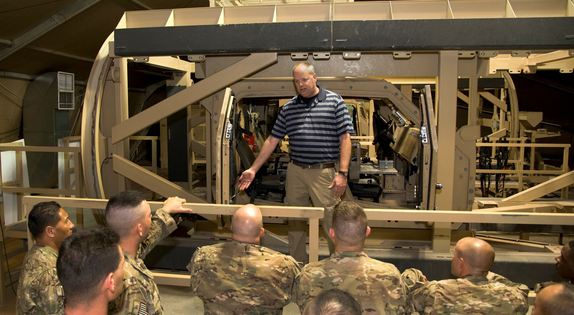 Philip Atkinson, Joint Readiness Staging Onward Movement and Integration senior training and development specialist, briefs a team assisting with Mine Resistant Ambush Protected vehicle rollover simulator training at Transit Center at Manas, Kyrgyzstan, July 5, 2013. The JRSOI unit at TCM teaches MRAP egress refresher training to all U.S. forces including civilians prior to deploying to Afghanistan. (U.S. Air Force photo/Staff Sgt. Krystie Martinez)