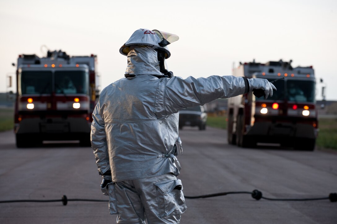 A member of the 28th Civil Engineer Squadron Fire Department directs fellow Airmen as they work on a mobile aircraft arresting system following a landing simulation during a phase II operational readiness exercise at Ellsworth Air Force Base, S.D.  July 11, 2013. The Fire Department is responsible for responding to the MAAS being tripped, unhooking the aircraft and resetting the cable within a limited time to ensure system availability. (U.S. Air Force photo by Airman 1st Class Alystria Maurer/Released)