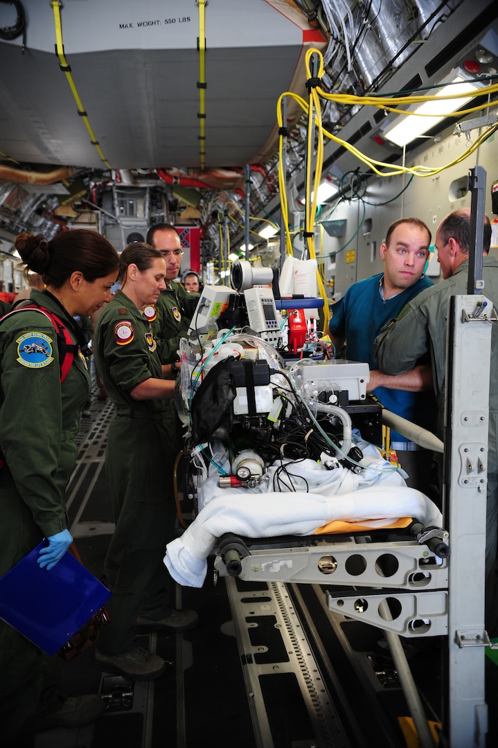 A specialized medical team ensures a patient is safe and ready for takeoff, July 10, 2013, Ramstein Air Base, Germany. An active duty Air Force crew made history while flying specialized medical teams and their patient requiring medical equipment never before used on board a Transatlantic mission. (U.S. Air Force photo/Senior Airman Hailey Haux)