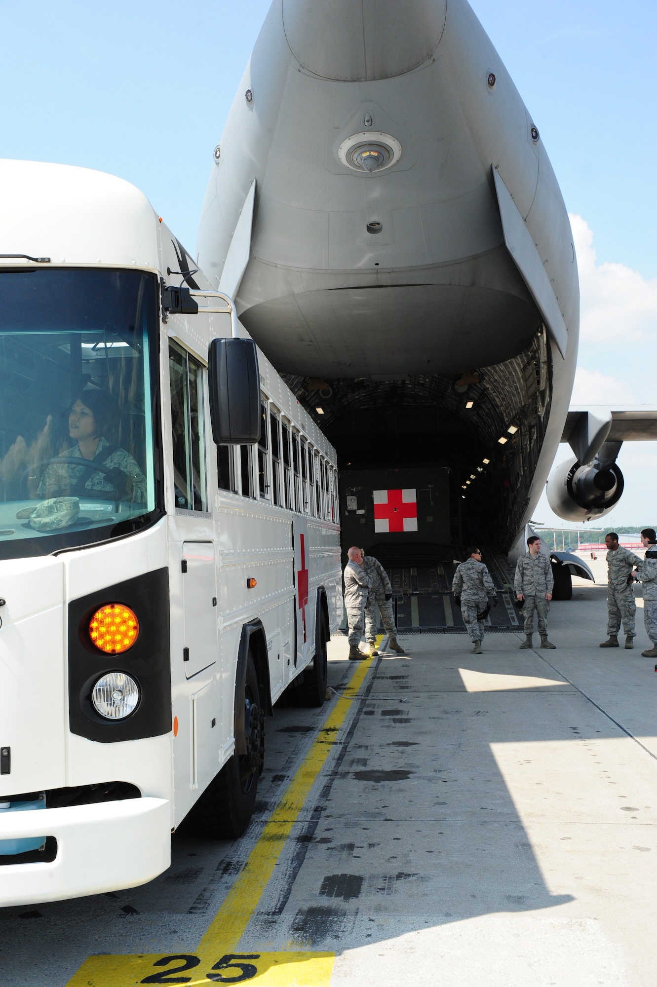 Service members wait outside a C-17 Globemaster III to assist in transferring a patient, July 10, 2013, Ramstein Air Base, Germany. An active duty Air Force crew made history while flying specialized medical teams and their patient requiring medical equipment never before used on board a Transatlantic mission. (U.S. Air Force photo/Senior Airman Hailey Haux)