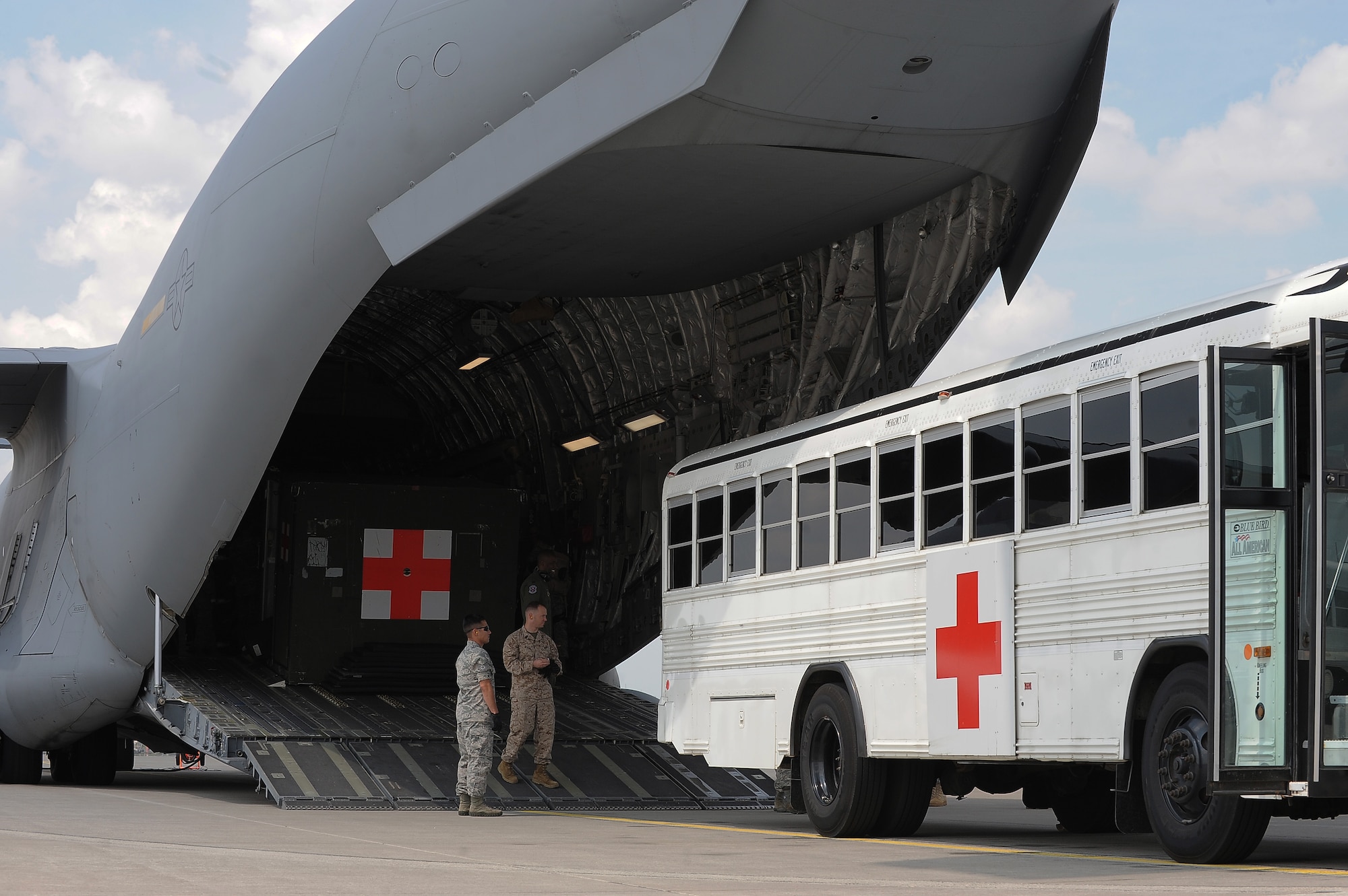 Service members wait outside a C-17 Globemaster III to assist in transferring a patient, July 10, 2013, Ramstein Air Base, Germany. An active duty Air Force crew made history while flying specialized medical teams and their patient requiring medical equipment never before used on board a Transatlantic mission. (U.S. Air Force photo/Senior Airman Hailey Haux)