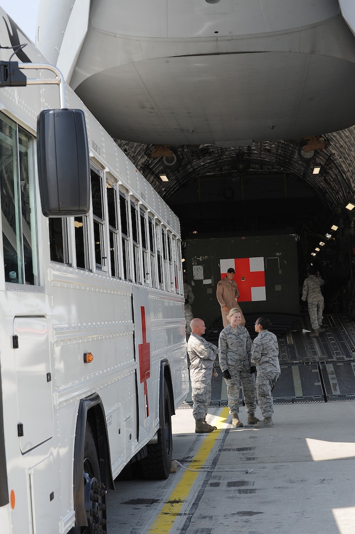 Service members wait outside a C-17 Globemaster III to assist in transferring a patient, July 10, 2013, Ramstein Air Base, Germany. An active duty Air Force crew made history while flying specialized medical teams and their patient requiring medical equipment never before used on board a Transatlantic mission. (U.S. Air Force photo/Senior Airman Hailey Haux)