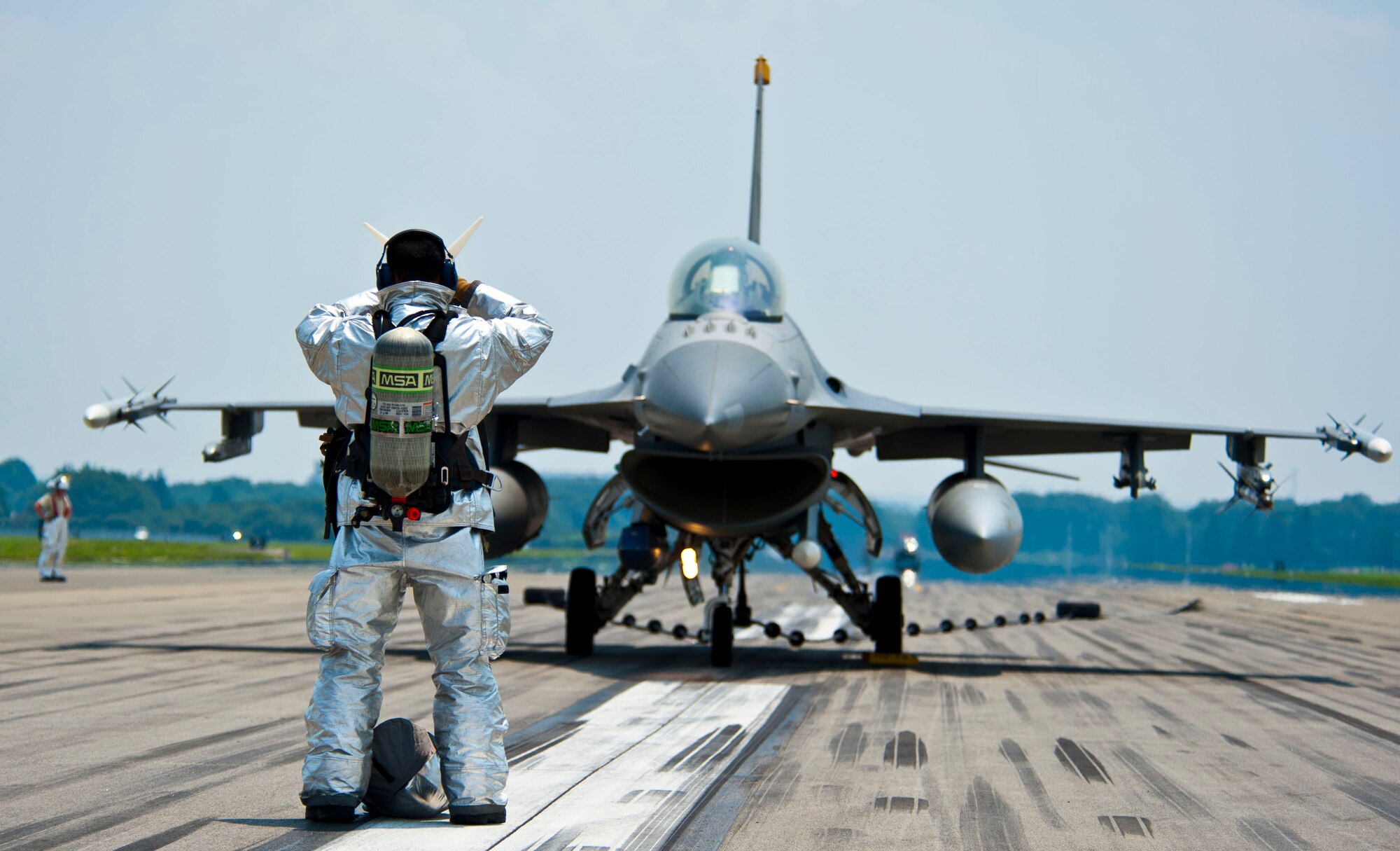 YOKOTA AIR BASE, Japan – A firefighter from 374th Civil Engineer Squadron gives direction to an F-16 Fighting Falcon pilot at Yokota Air Base, Japan, July 10, 2013.  Several different departments from 374 CES, including fire department, participated during the arresting gear testing.  Two F-16’s from Misawa Air Base, Japan, assisted with testing the system.   (U.S. Air Force photo by Airman 1st Class Soo C. Kim)