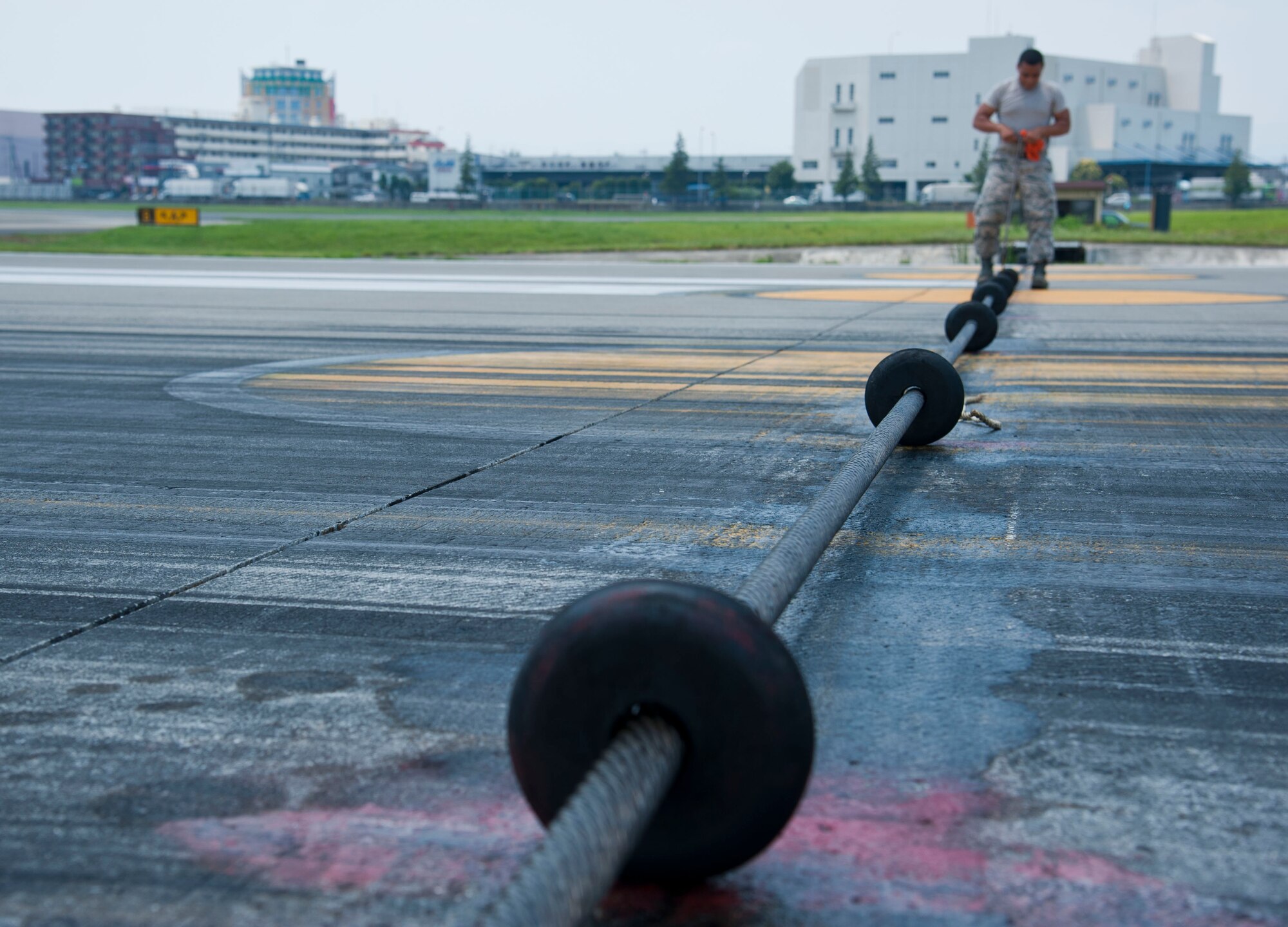 YOKOTA AIR BASE, Japan – Airman 1st Class Matthew Struve, an electrical power production technician with the 374th Civil Engineer Squadron, evenly spaces the doughnuts along the emergency landing system cable at Yokota Air Base, Japan, July 10, 2013.  The doughnuts are used to lift the cable above the ground level, making it easier for the aircraft’s tailhook to catch the cable, part of the arresting gear mechanism that assists with rapidly decelerating aircraft during landing. (U.S. Air Force photo by Airman 1st Class Soo C. Kim)
