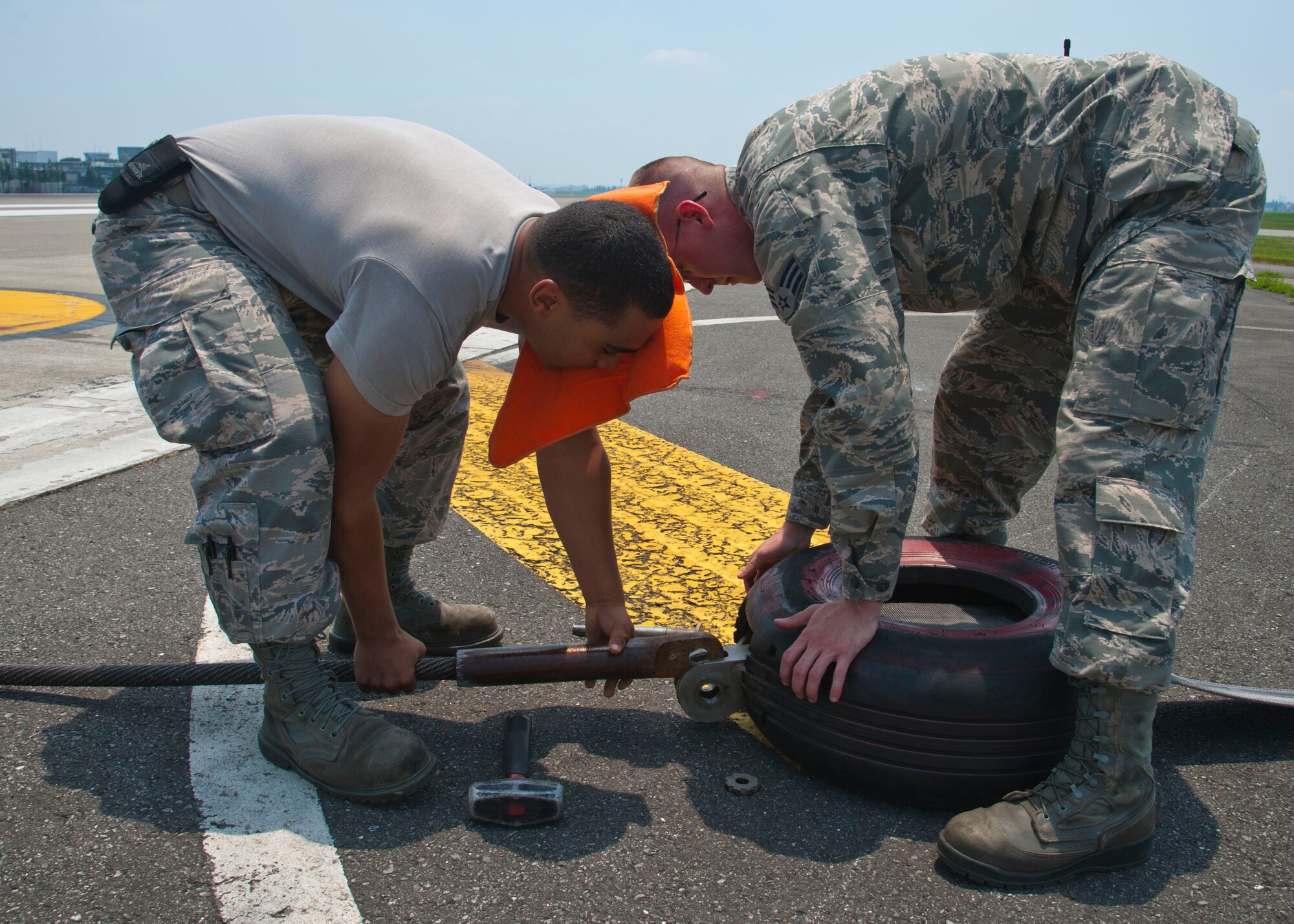 YOKOTA AIR BASE, Japan – Senior Airman Johnathan Riley and Airman 1st Class Matthew Struve, both electrical power production technicians with the 374th Civil Engineer Squadron, connect cables to prepare flightline arresting gear for barrier testing at Yokota Air Base, Japan, July 10, 2013.  The arresting gear is a mechanical system used to rapidly decelerate an aircraft during landing.  (U.S. Air Force photo by Airman 1st Class Soo C. Kim)