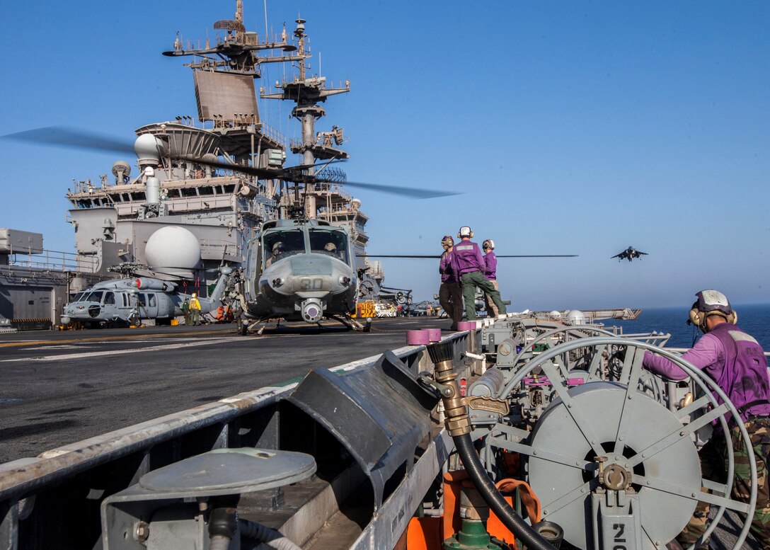 A U.S. Marine Corps AV-8B Harrier assigned to Marine Medium Tiltrotor Squadron (VMM) 266 (Reinforced), 26th Marine Expeditionary Unit (MEU), prepares to land as a AH-1W Super Cobra prepares to takeoff from the flight deck of the USS Kearsarge (LHD 3), at sea, July 13, 2013.  The 26th MEU is a Marine Air-Ground Task Force forward-deployed to the U.S. 5th Fleet area of responsibility aboard the Kearsarge Amphibious Ready Group serving as a sea-based, expeditionary crisis response force capable of conducting amphibious operations across the full  range of military operations. (U.S. Marine Corps photo by Sgt. Christopher Q. Stone/Released)