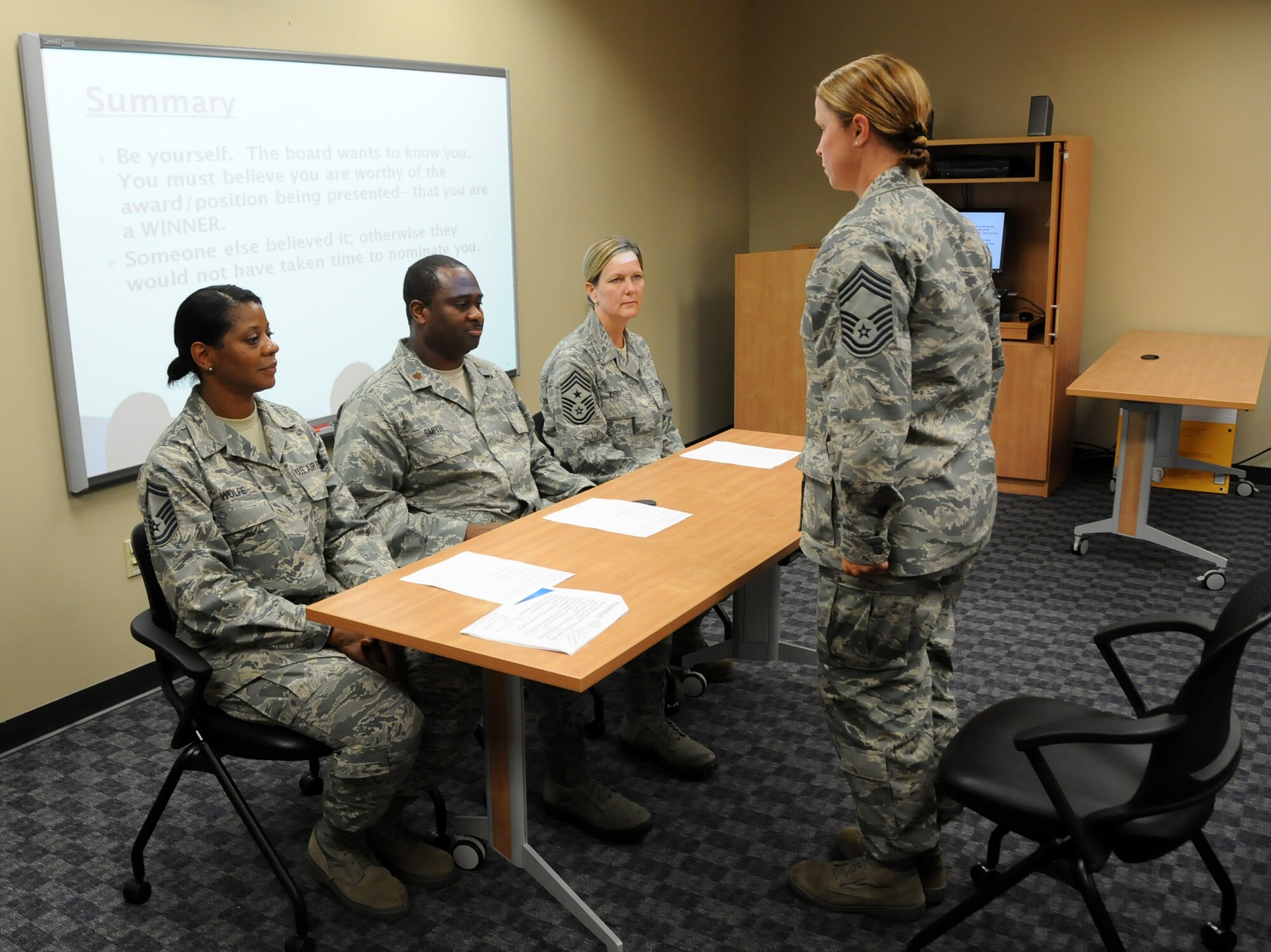 Chief Master Sgt. Kimberly R. Holloway, 192nd Fighter Wing Operations Group chief, demonstrates the correct way to present oneself during a board interview in the “Mock Interview Board” presented by the Junior Enlisted Council, July 13, 2013. The class received a briefing on how to prepare for a board interview and the procedures of meeting the board. Airmen were also able to sharpen their interview skills by volunteering to practice in front of the mock board. (U.S. Air National Guard photo by Airman 1st Class Johnisa B. Roberts/Released)