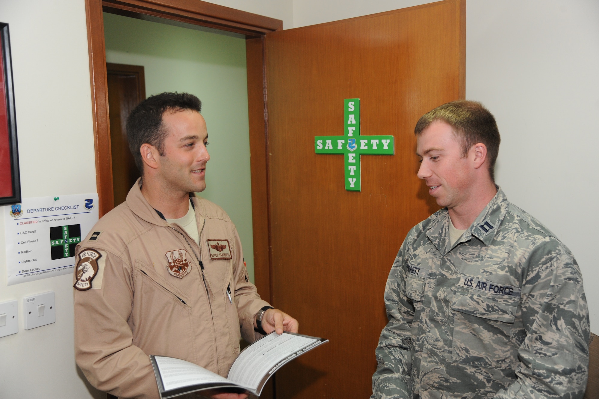 U.S. Air Force Capt. Brett VanderPas, left, 380th Air Expeditionary Wing chief of flight safety, speaks with U.S. Air Force Capt. Zach Garrett, 380th Expeditionary Medical Group aerospace physiologist, in the safety office at an undisclosed location in Southwest Asia July 10, 2013. The safety office and the aerospace physiologist work closely together to monitor trends preventable by changing human factors. (U.S. Air Force photo by Senior Airman Jacob Morgan) 