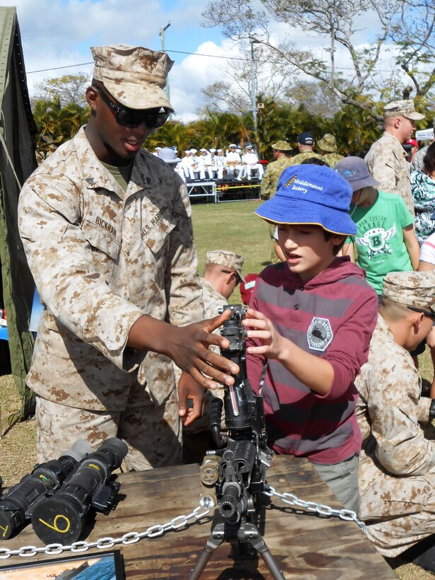 Corporal Dante Bickham, a mortarman with Battalion Landing Team 2nd Battalion, 4th Marines, 31st Marine Expeditionary Unit, and a native of Houston, Texas, explains the nomenclature of an M249 squad automatic weapon to a young Australian boy during the opening ceremony for exercise Talisman Saber, here, July 14. The Marines and Sailors of the 31st MEU, PHIBRON 11, and Expeditionary Strike Group 7 will train alongside a joint U.S. force that totals approximately 18,000 personnel, as well as approximately 9,000 Australian service members in the fifth iteration of Talisman Saber, a month-long biennial exercise designed to enhance multilateral collaboration in support of future combined operations, natural disaster, humanitarian and emergency response. 