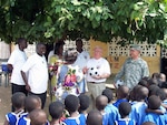 Doug Friez, a project advisor with the State Partnership Program, presents a soccer ball to a teacher at a school in Ghana, Africa. Friez and Lt. Col. Mark Tibor (right) were in the country to provide a Disaster Management Workshop. At left are employees with Ghana's National Disaster Management Organization, or NADMO, who participated in the workshop.