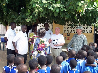 Doug Friez, a project advisor with the State Partnership Program, presents a soccer ball to a teacher at a school in Ghana, Africa. Friez and Lt. Col. Mark Tibor (right) were in the country to provide a Disaster Management Workshop. At left are employees with Ghana's National Disaster Management Organization, or NADMO, who participated in the workshop.