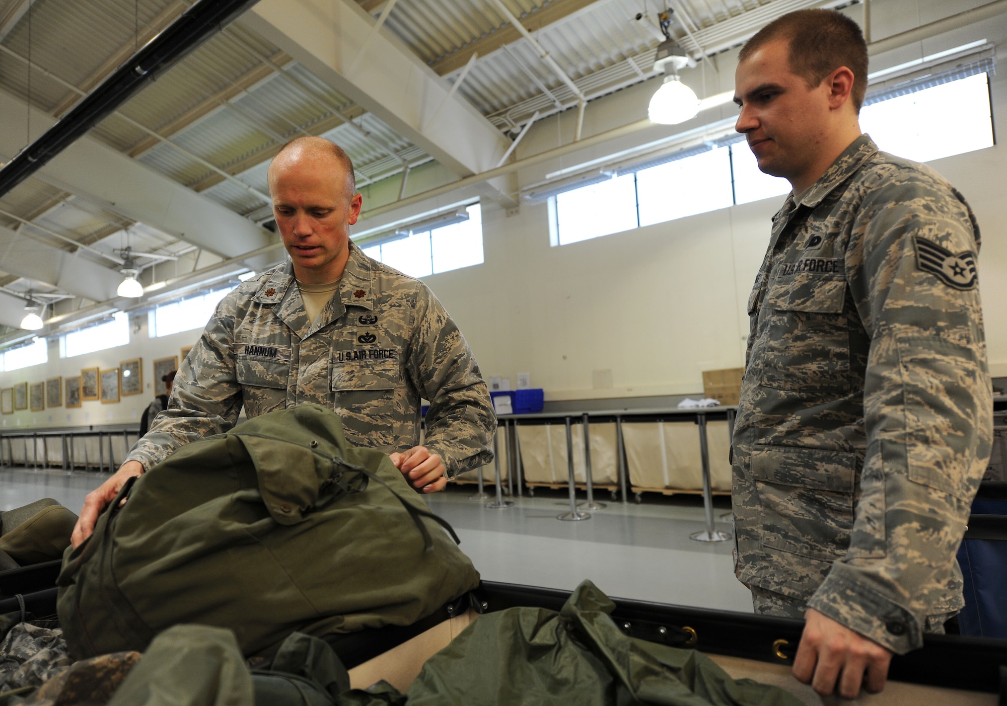 Maj. Kelly Hannum, 336th Training Support Squadron commander, builds an SV80 bag with Staff Sgt. Nicholas Waggle, 336th TRSS assistant NCO in charge of the warehouse, at Fairchild Air Force Base, Wash., July 9, 2013. Survival, evasion, resistance and escape students are given the SV80 bag which contains all the gear they will need for the woods such as bolt knives, aircrew vests, signal mirror, iodine, map, canteens, ponchos and more. (U.S. Air Force photo by Airman 1st Class Janelle Patiño/Released)