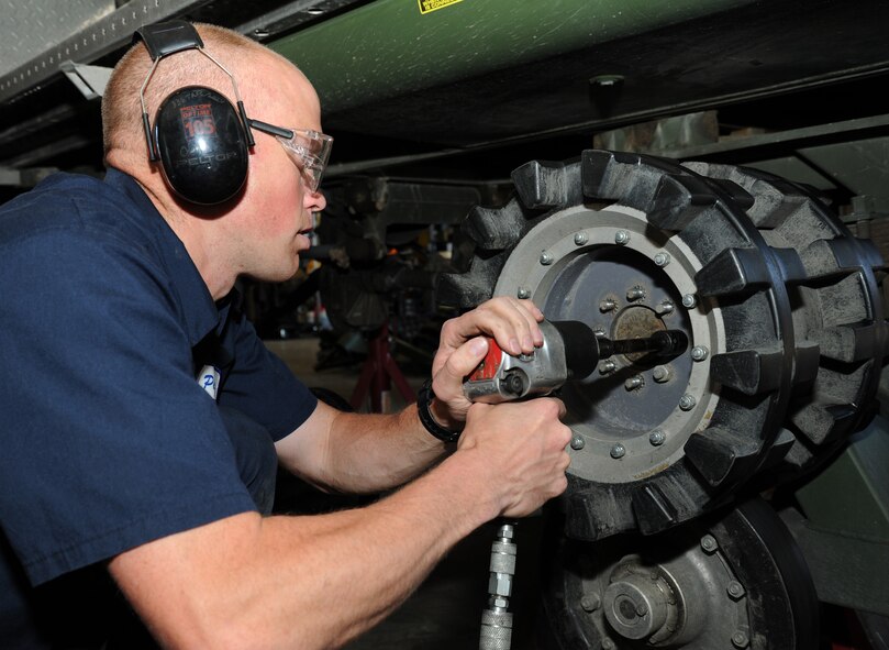 Maj. Kelly Hannum, 336th Training Support Squadron commander, removes the bolts holding the main drive wheel for the track assembly onto the axle assembly of a Tucker Terra Sno-Cat at Fairchild Air Force Base, Wash., July 9, 2013. Hannum was diagnosed with Tourette Syndrome when he joined the Air Force in 1998. (U.S. Air Force photo/Airman 1st Class Janelle Patiño)