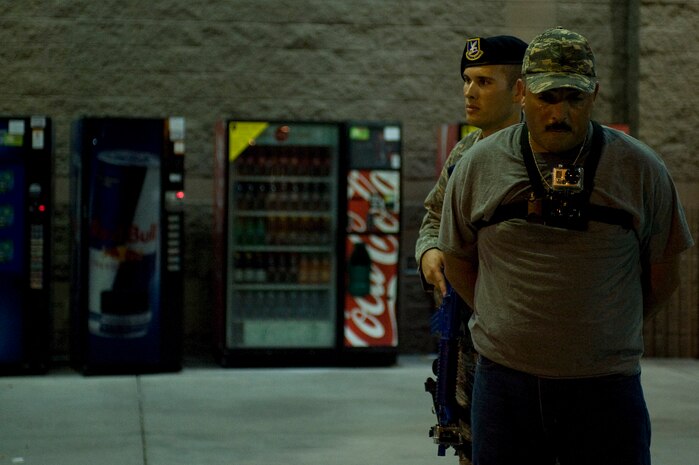 Staff Sgt. Jordan Young, 99th Security Forces Squadron law enforcement desk controller, escorts a suspect, played by Master Sgt. David Paxton, 99th SFS NCO in charge of security forces training, to a patrol vehicle during an active-shooter exercise at the Exchange July 9, 2013, at Nellis Air Force Base, Nev. SFS Airmen develop force protection doctrine, programs and policies by planning and programming resources to execute the missions of weapon system security, physical and information security, integrated base defense, combat arms, law enforcement, antiterrorism, resource protection and corrections. (U.S. Air Force photo by Airman 1st Class Christopher Tam)
