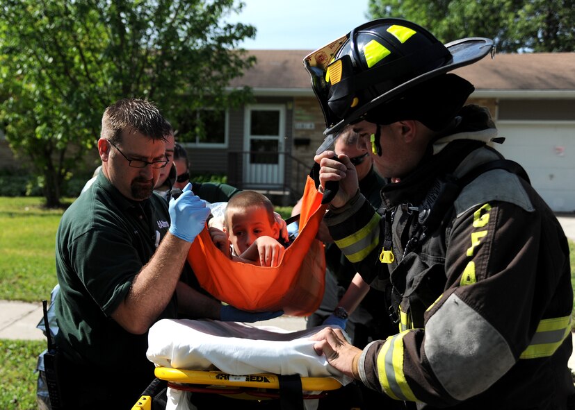 Firefighters from the 319th Civil Engineer Squadron work with Altru Health System medics to escort a “victim” during a tornado exercise on June 21, 2013, on Grand Forks Air Force Base, N.D. The 319th Air Base Wing teamed up with off-base first-responders from the city of Grand Forks to hone their joint response capabilities if a real tornado struck the base. (U.S. Air Force photo/Airman 1st Class Ashley Nicole Taylor)