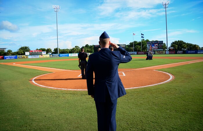 Airman 1st Class Michael Reeves, 628th Air Base Wing Public Affairs broadcaster, salutes as the Joint Base Charleston Honor Guard marches off the field during Military Appreciation Night July 13, 2013, at the Joseph P. Riley Jr. ballpark in Charleston, S.C. Reeves sang the National Anthem to a crowd of more than 5,000 fans. (U.S. Air Force photo/ Staff Sgt. Anthony Hyatt)