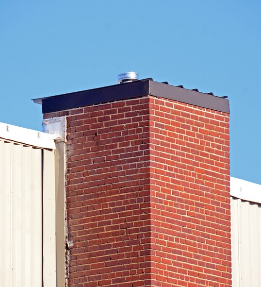 Contractors from A1 Construction trim chimneys at the 94th Airlift Wing headquarters building and cap them with metal ventilators. The ventilators will protect birds and debris from falling into chimneys. (U.S. Air Force photo/Brad Fallin)