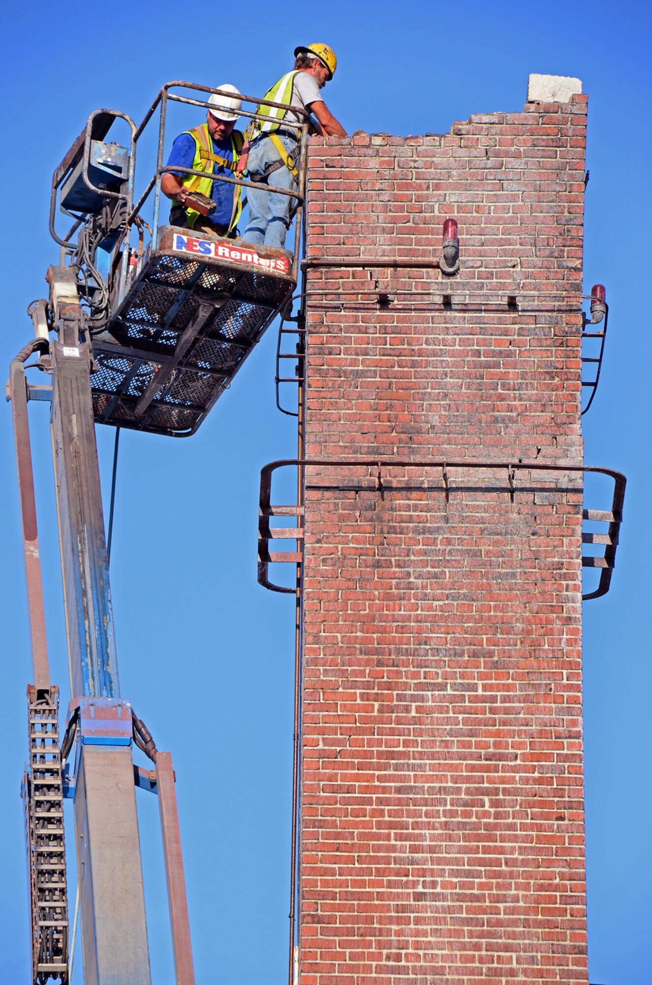 Contractors from A1 Construction trim chimneys at the 94th Airlift Wing headquarters building and cap them with metal ventilators. The ventilators will protect birds and debris from falling into chimneys. (U.S. Air Force photo/Brad Fallin)