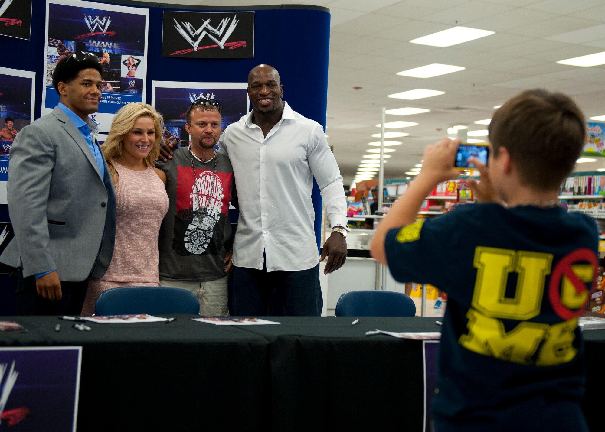 Joint Base Langley-Eustis community members take a group photo with WWE Superstars Darren Young and Titus O’Neil, and WWE Diva Natalya at the Exchange on Langley Air Force Base, July 9, 2013. The WWE entertainers signed autographs and took photos with Joint Base Langley-Eustis Soldiers, Airmen and their families. (U.S. Air Force photo by Staff Sgt. John D. Strong II/Released)