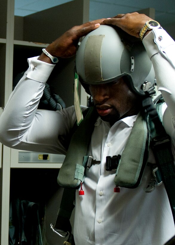 WWE Superstar Titus O’Neil dons a HGU-55P aircraft helmet at the 94th Fighter Squadron at Langley Air Force Base, July 9, 2013. While on Langley, the WWE entertainers received a mission brief on the F-22A Raptor and its capabilities. (U.S. Air Force photo by Staff Sgt. John D. Strong II/Released)