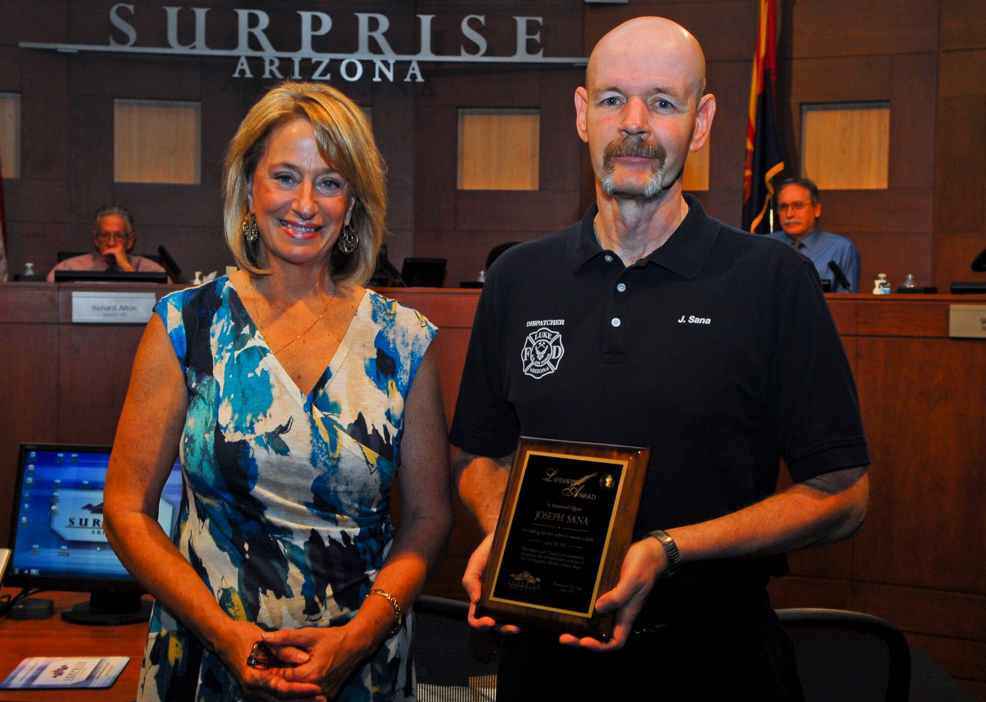 Surprise Mayor Sharon Wolcott and Joseph Sana, 56th Civil Engineer Squadron 911 dispatcher, pose for a photo June 25 at a ceremony where he received a lifesaving award for actions he took April 19 to save a young girl from a dog attack. The ceremony took place at Surprise City Hall. (U.S. Air Force photo/Senior Airman David Owsianka)