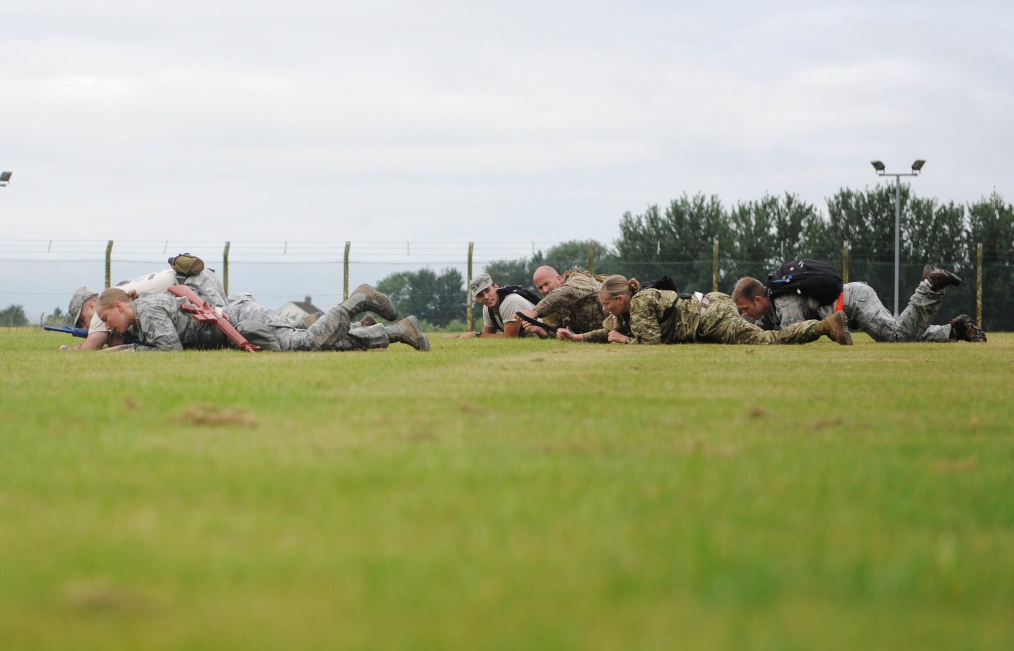 Monster Mash competitors low crawl across a field July 3, 2013 during the 352nd Special Operations Group Olympics on RAF Mildenhall, England. The Monster Mash consisted of various events such as carrying a Zodiac inflatable boat and marching with a 40-pound rucksack. (U.S. Air Force photo by Airman 1st Class Preston Webb/Released)