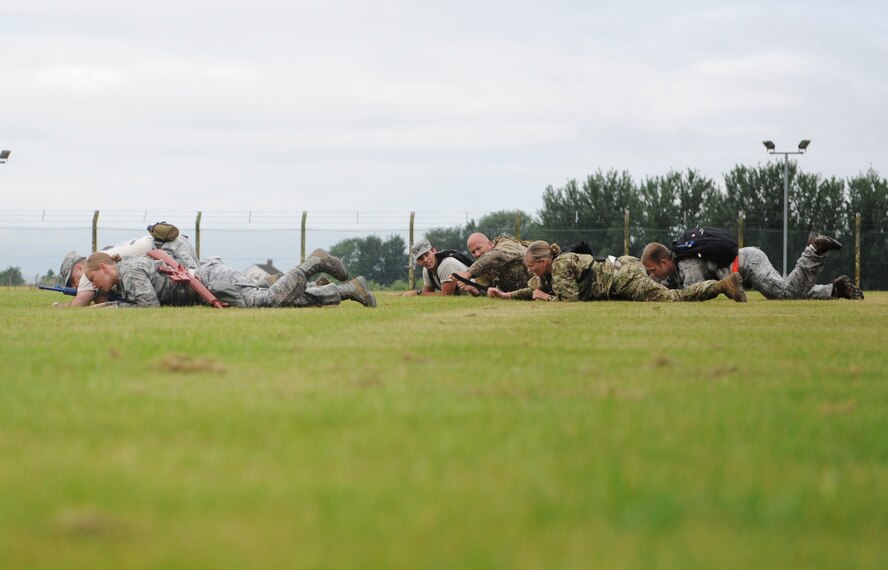 Monster Mash competitors low crawl across a field July 3, 2013 during the 352nd Special Operations Group Olympics on RAF Mildenhall, England. The Monster Mash consisted of various events such as carrying a Zodiac inflatable boat and marching with a 40-pound rucksack. (U.S. Air Force photo by Airman 1st Class Preston Webb/Released)