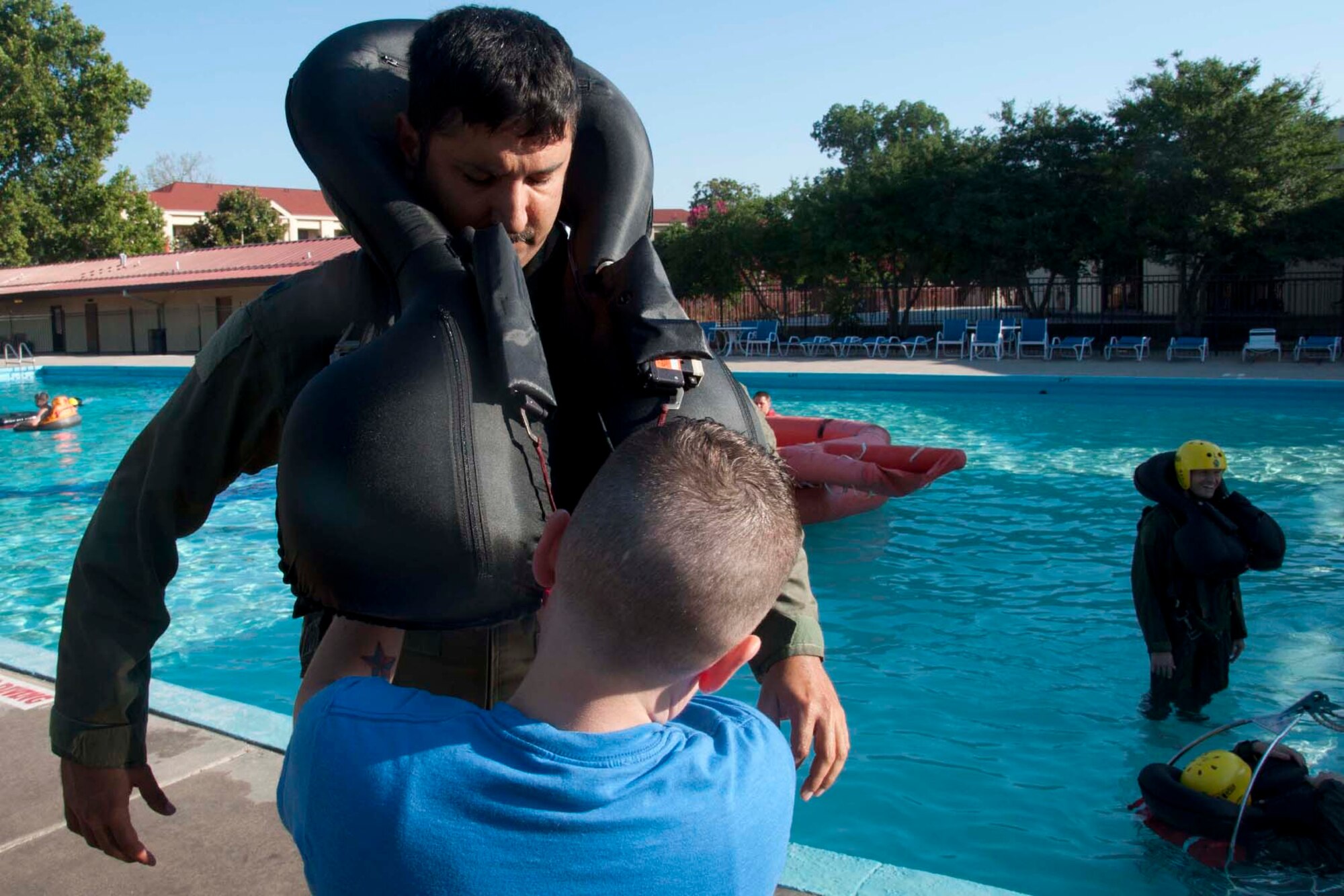 U.S. Air Force Lt. Col. Marc Kurup, 343rd Bomb Squadron Radar Navigator, watches as safety gear is strapped in place prior to taking part in water survival training at Barksdale Air Force Base, La., July 13, 2013.  The refresher course is required every three years for all air crew members.  Participants take part in four different stations and are coached on how to get away from a parachute and deploy and use various life-saving devices including rafts and helicopter lifts. ( U.S. Air Force photo by Tech. Sgt. Ted Daigle/Released)