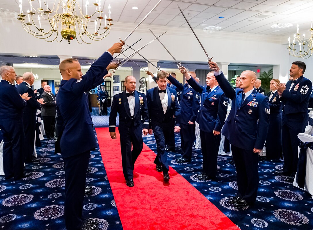 Brig. Gen. Kevin J. Jacobsen, OSI commander, left, and OSI Command Chief Master Sgt. John Fine, walk through a sword salute while on their way up to their seats during the Order of the Sword induction ceremony held July 8. (U.S. Air Force photo/Mike Hastings)