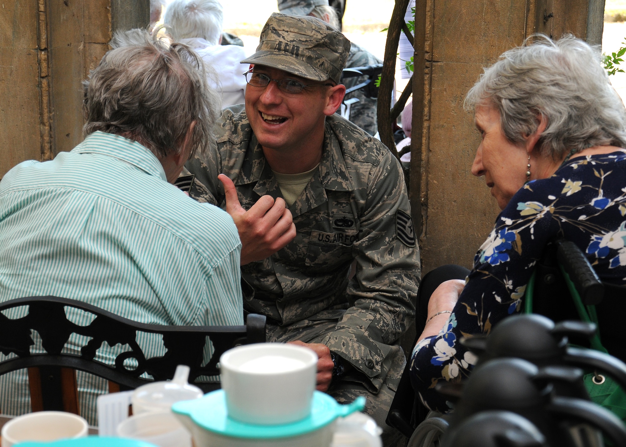 Tech. Sgt. Daniel Glynn, 100th Maintenance Group foreign object damage and dropped object prevention monitor from Victorville, Calif., shares a joke with residents at Stowlangtoft Hall nursing home July 11, 2013, in Suffolk, England. Twelve service members and Department of Defense personnel from Team Mildenhall volunteered to speak to residents, some of whom are Royal Air Force veterans, about their time in the U.S. Air Force. (U.S. Air Force photo by Gina Randall/Released)