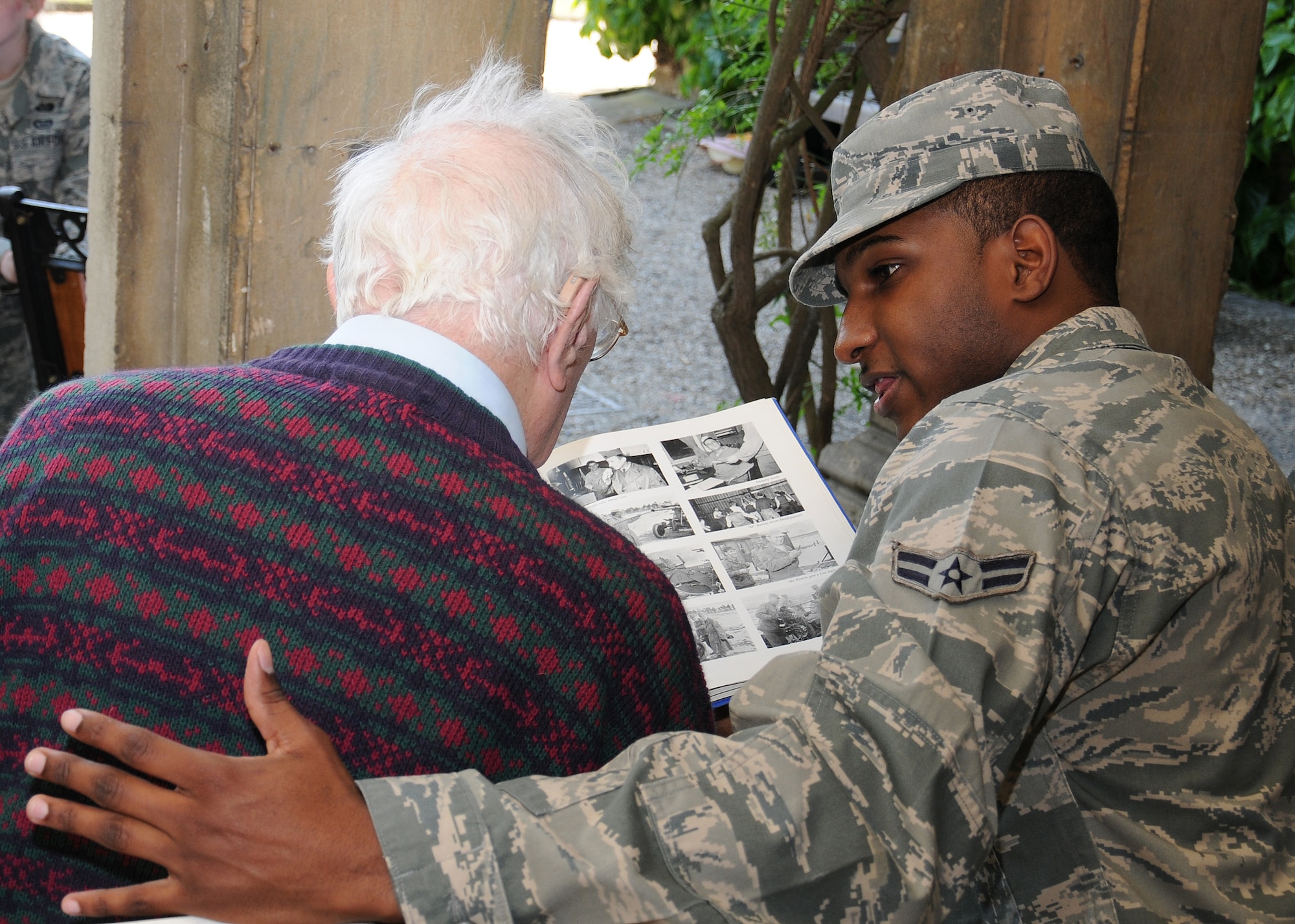 Airman 1st Class Ryan Dowtin Jr., 100th Maintenance Squadron non-destruction inspection apprentice from Greenwood, S.C., shares photographs from World War II with a resident at Stowlangtoft Hall nursing home July 11, 2013, in Suffolk, England. Twelve service members and Department of Defense personnel from Team Mildenhall volunteered to speak to residents, some of whom are Royal Air Force veterans, about their time in the U.S. Air Force. (U.S. Air Force photo by Gina Randall/Released)