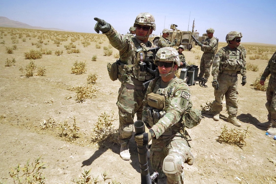 U.S. Army Sgt. Robert Avila, left, points in the direction to guide U.S ...